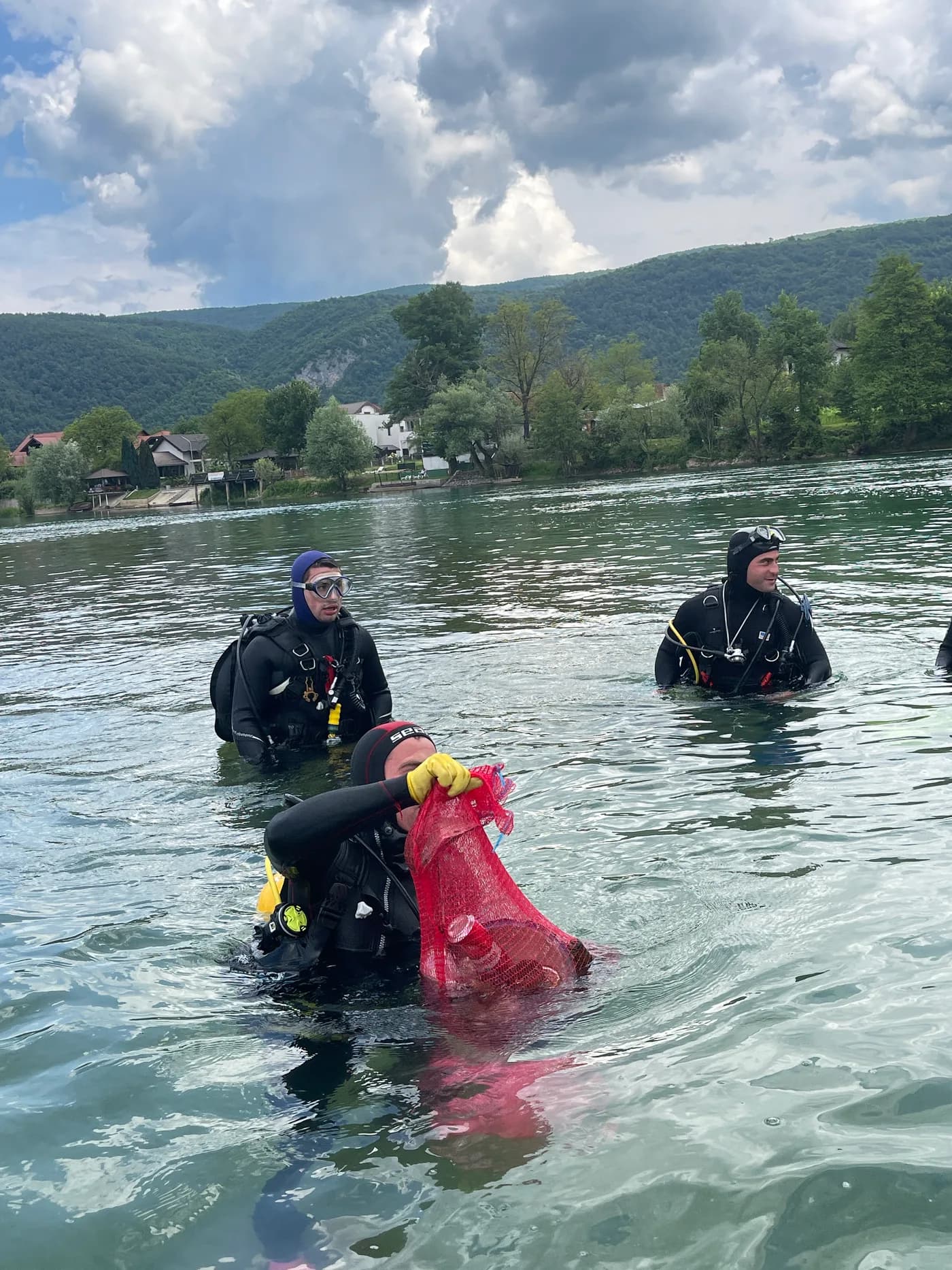 Divers in the Una River with a collected bag of material from the cleanup.