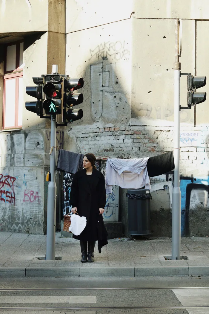The same corner again, the woman in black with her back half turned, the line of washing above.